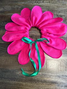 a pink flower with a green ribbon tied around it on a wooden table next to a pair of scissors