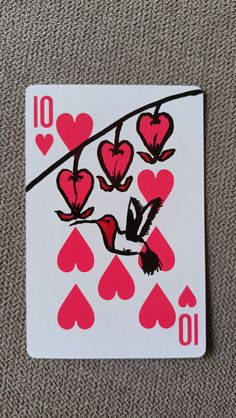 a playing card with hearts and birds on the front, sitting on a carpeted surface