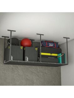 a shelf filled with boxes and other items on top of a cement wall next to a red ball