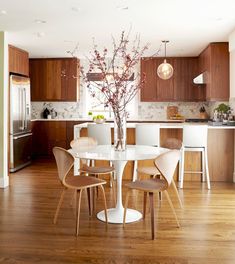 a kitchen and dining room with wood flooring, white table and chairs in the center