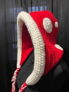 a red and white knitted hat on top of a mannequin's head