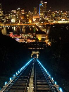 an overhead view of a city at night with lights on the tracks and buildings in the background