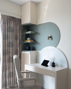 a white desk with a laptop on top of it next to a chair and window