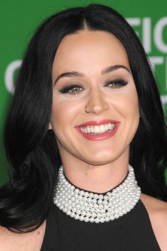 a close up of a person wearing a necklace with pearls on it and smiling at the camera