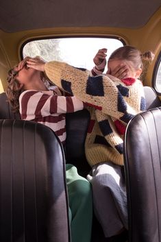 two women sitting in the back seat of a car with their arms around each other