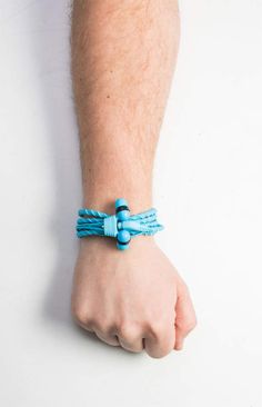 a man's arm with a blue bracelet on it