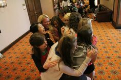 a group of women hugging each other in a hallway