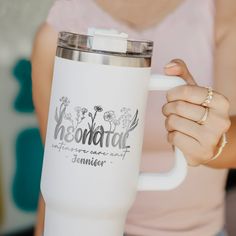 a woman holding a white coffee mug with the words restoration written on it and flowers