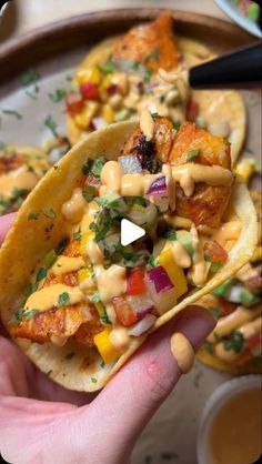 someone is holding up some tacos with toppings on them in front of the camera