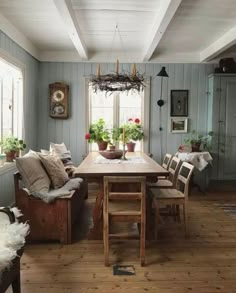 a dining room table with chairs and potted plants