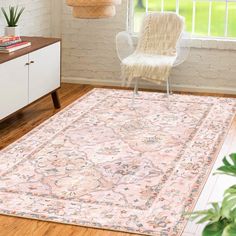 a pink rug with an ornate design on the floor in a living room next to a white chair