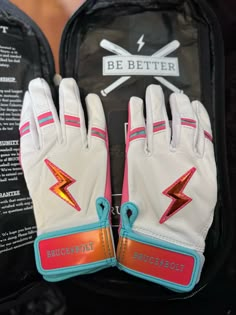 a pair of white leather gloves with pink and blue trims on the palm of someone's hand