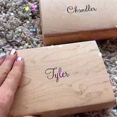 a person holding a wooden box with the word chandler on it and another hand next to it