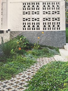 an image of a house that is in the grass with flowers and plants around it