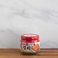 a jar of chinese food sitting on top of a wooden table next to a white marble wall