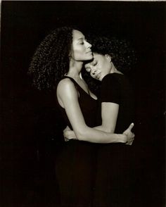 two women embracing each other in black and white