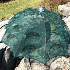 a green umbrella sitting on top of a rock next to some grass and rocks in the background