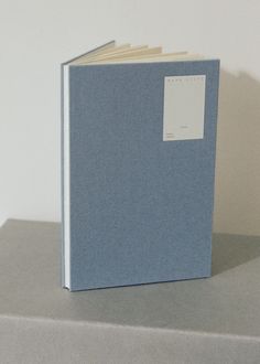 a blue book sitting on top of a gray table next to a white wall with a tag