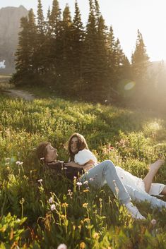 a man and woman laying in the grass with trees in the backgroung