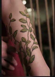 a woman's arm with green leaves on it