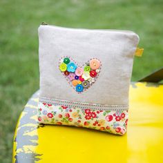 a small purse with buttons on it sitting on a yellow table