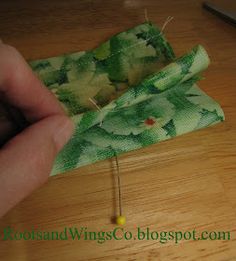 someone is sewing something on a piece of green fabric with needles and thread in it