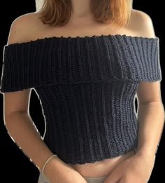 a woman with red hair wearing a black off the shoulder knitted top and holding her hands in her pockets