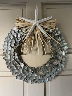 a wreath made out of seashells with a star hanging on the front door