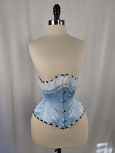 Alice in Wonderland Satin Steel Boned Mid Hip Underbust Corset This listing is for a made to order corset made using our custom pattern! Constructed from a stunning light blue satin with a cotton twill liner, this corset is perfect for victorians, cosplayers and goths alike.  This corset is made of a light blue satin, tied together with, white lace trimming, harlequin binding, white stitching, white laces, silver colored hardware, and a floating harlequin boned lacing panel.   Our 226 Pattern is Blue And White Corset, Light Blue Corset, Sweet 16 Makeup, Wonderland Sweet 16, Alice Costume, Alice In Wonderland Dress, Gala Ideas, Water Fairy, Couples Costume