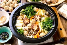 a bowl filled with seafood and vegetables next to chopsticks on top of a wooden table