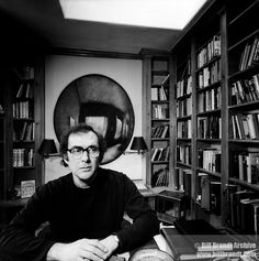 a man sitting in front of a book shelf filled with books