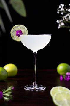 a margarita with a flower on the rim and garnished with limes next to it