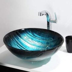 a glass bowl sink sitting on top of a counter next to a faucet