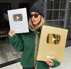 a woman holding up two boxes with an apple logo on one side and another in the other