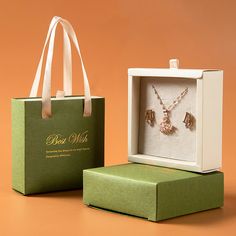 a box with two necklaces in it next to a green bag that says best mom