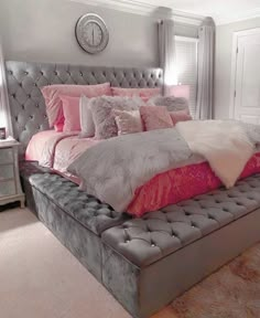 a large bed with pink and grey pillows