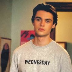 a young man standing in front of a mirror wearing a sweatshirt that says wednesday on it