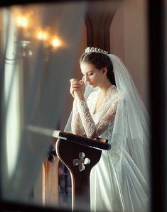 a woman in a wedding dress standing at a podium with her hands clasped to her chest