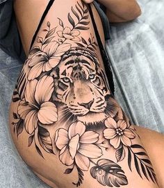 a woman's leg with a tiger and flowers tattoo on it