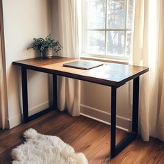 a laptop computer sitting on top of a wooden desk in front of a large window