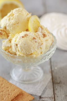 two scoops of ice cream in a glass bowl with crackers on the side