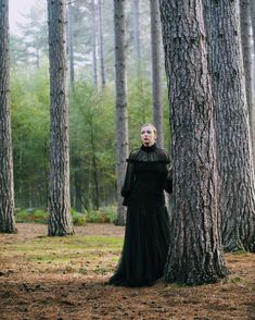 a woman standing in the middle of a forest