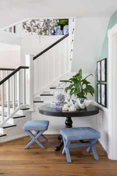 there is a small table with two stools next to it and a potted plant on the table