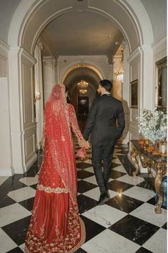 a man and woman in formal wear walking down a hall way with black and white checkered flooring