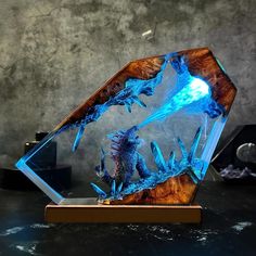 a blue dragon sculpture sitting on top of a wooden stand next to a black wall