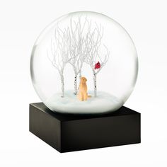 a snow globe with a dog and bird in the snow on it's base