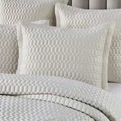 a close up of a bed with white sheets and pillows