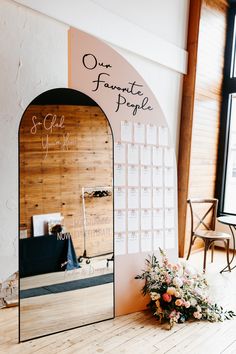 a mirror sitting on top of a wooden floor next to a vase filled with flowers