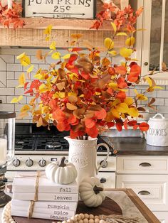 a white vase filled with orange and yellow leaves