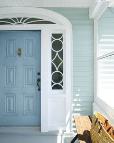 a blue front door with a bench in front of it and a basket on the side